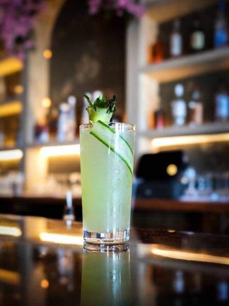 Refreshing cucumber highball cocktail served at the dimly lit bar counter of Coca Bar & Lounge.