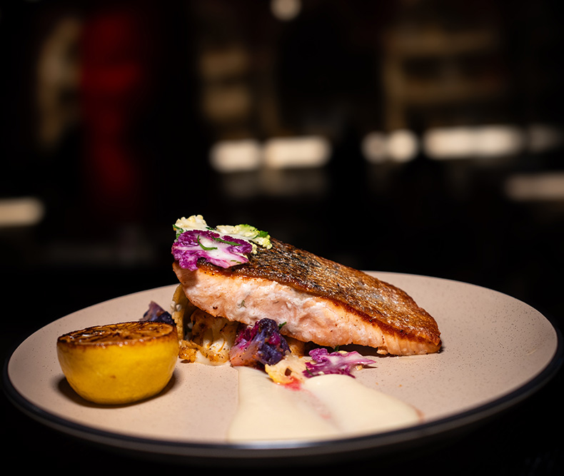 Pan-seared fish entrée with roasted lemon and garnish served at Coca Lounge in Hicksville NY